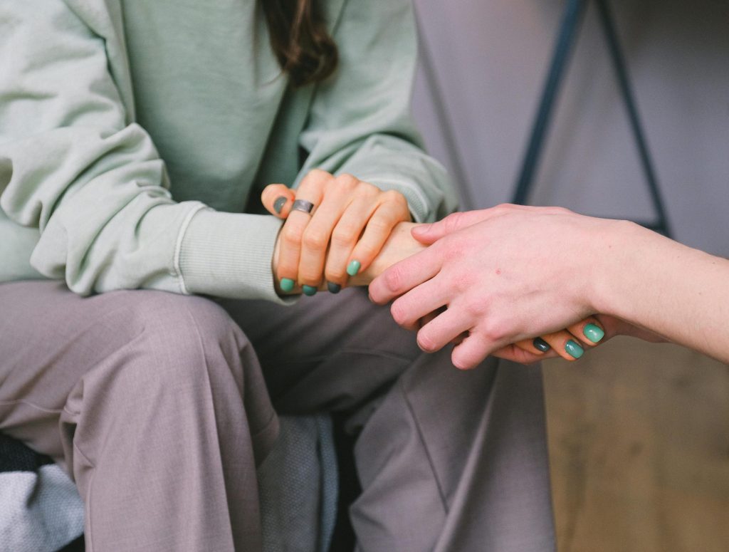 Close-up of two people holding hands during a comforting therapy session.