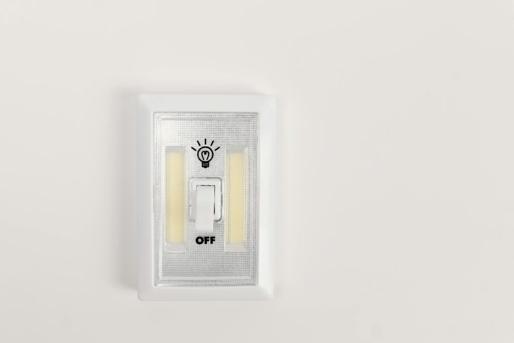 Minimalist light switch turned off on a plain white wall, offering ample copy space.